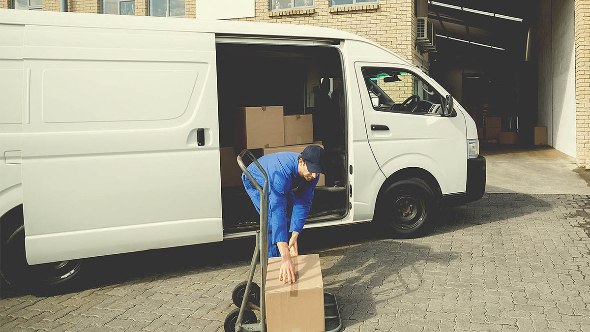 A man is loading boxes into a Sprinter van