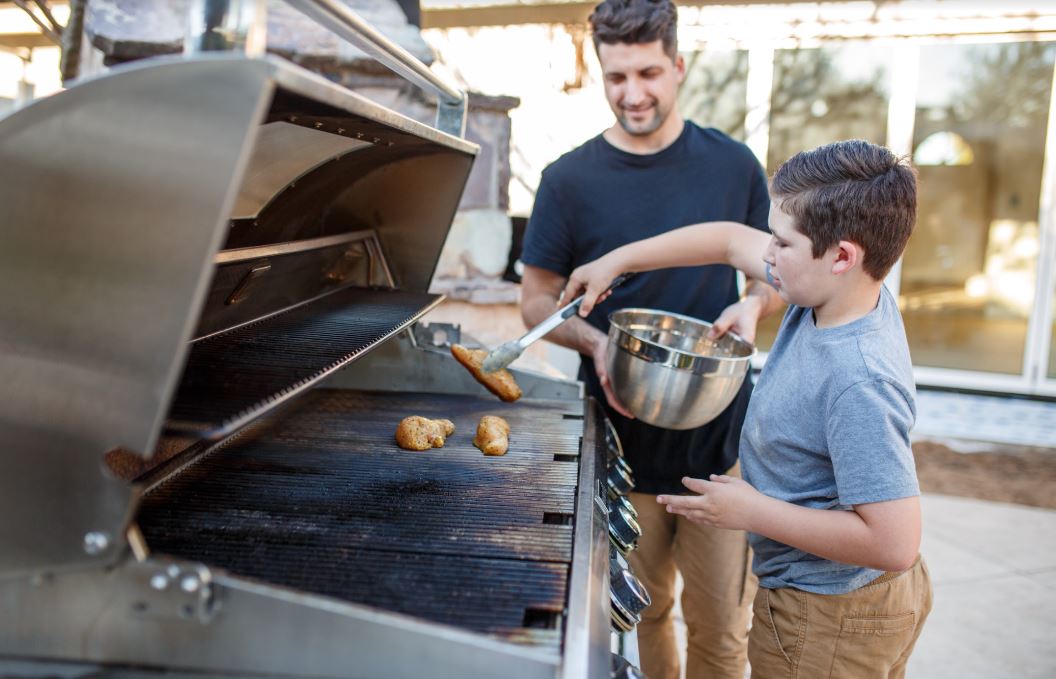 father and son grilling chicken